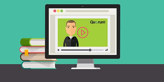 An illustration shows a computer monitor displaying an educational video player with a person on the screen and a "Quorum" label. The background is green, and a stack of books sits beside the monitor, all set against a teal backdrop.